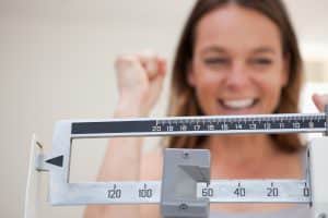 Scale showing weight loss to smiling woman after one meal a day