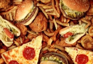 Fast food concept with greasy fried restaurant take out as onion rings burger and hot dogs with fried chicken french fries and pizza as a symbol of diet temptation resulting in unhealthy nutrition.