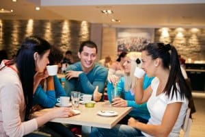 Five student friends communicating in cafe