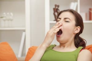 yawning woman sitting on sofa at home