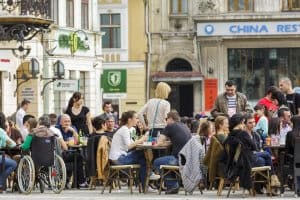 BRASOV, ROMANIA - MARCH 23: Unidentified locals and tourists socialize over a drink in a sidewalk cafe on March 23, 2014 in Council Square in Brasov, 7th largest and the most visited city in Romania.