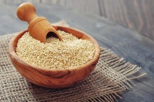 Raw quinoa seeds in the wooden bowl on wooden background closeup