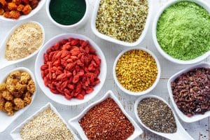 White bowls of various superfoods on white wooden background