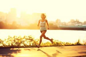 woman running in the sunset by the city