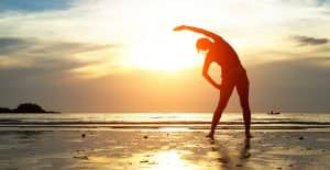 Silhouette young woman, exercise on the beach at sunset.