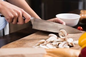 woman on cutting board slicing mushrooms