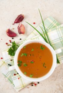 bone broth in a cup and herbs to show how it can help omad headaches