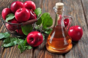 Apple cider vinegar in glass bottle and basket with fresh apples