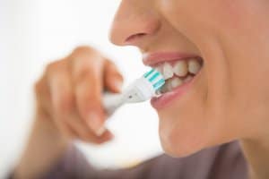 Closeup on young woman brushing teeth