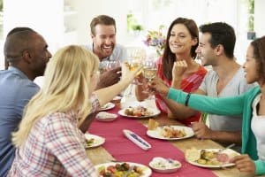 Group Of Friends Making Toast Around Table At Dinner Party