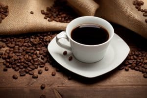 Cup of coffee and beans on jute background