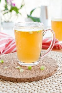 Homemade bone broth with leek in glass cup