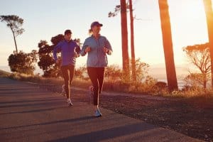 Running at sunrise couple exercising for marathon and workout fitness