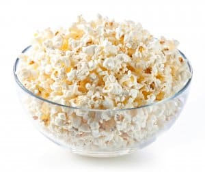 Glass bowl with popcorn on white background