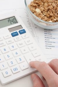 Healthy eating concept - man calculate his daily nutrition intake. Muesli in glass bowl, calculator, calendar and nutrition chart.