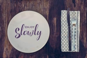 Enjoy slowly quote, healthy eating concept design with restaurant elements over retro style wood surface.