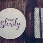 Enjoy slowly quote, healthy eating concept design with restaurant elements over retro style wood surface.