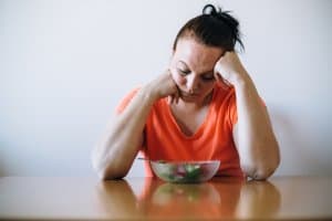 Unhappy overweight looking at salad. Diet concept.