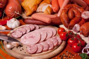 A variety of processed cold meat products, on a wooden cutting 