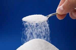 Heap of sugar and pouring more from a spoon