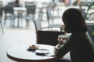 Pensive woman having breakfast in the café, view from the back